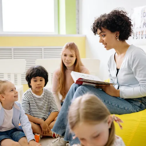 Group of kids listening to teacher during story time at school.