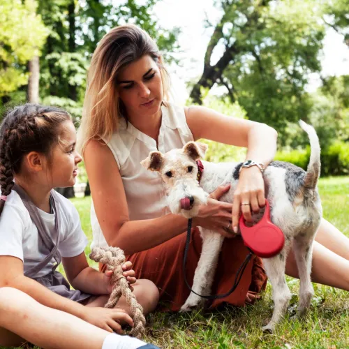 Mom and daughter sitting with dog outside.