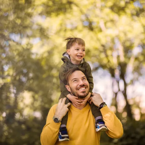 Son sitting on dad's shoulders, smiling.