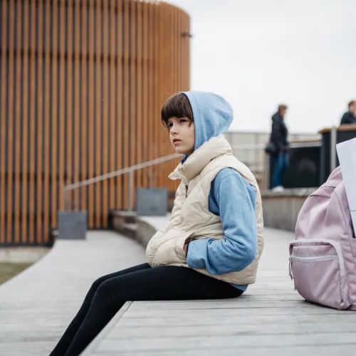 Girl waiting for their parent at school pickup.