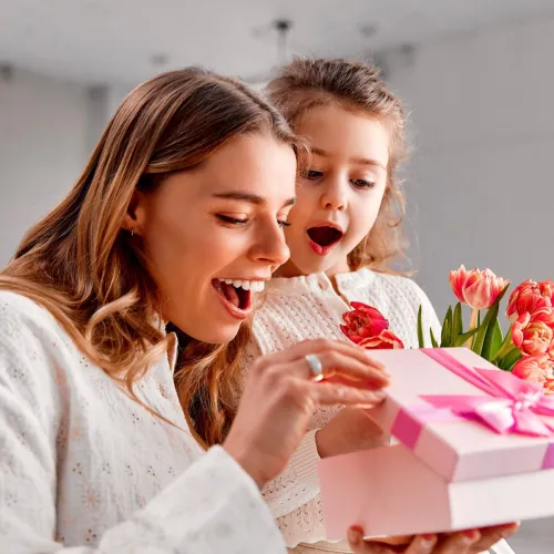 Mom and little girl opening a present, smiling.