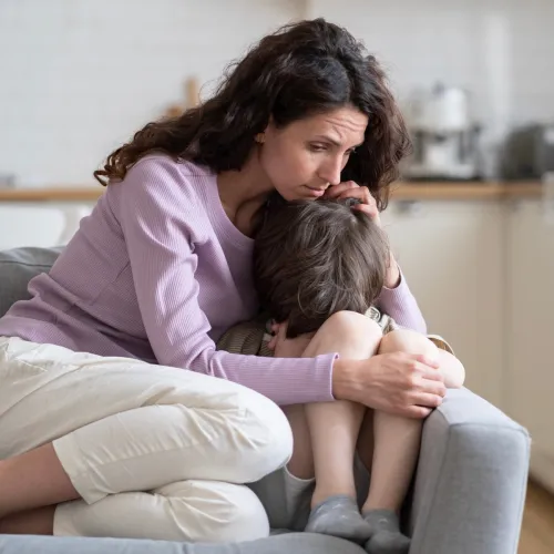 Mom comforting son on the couch.