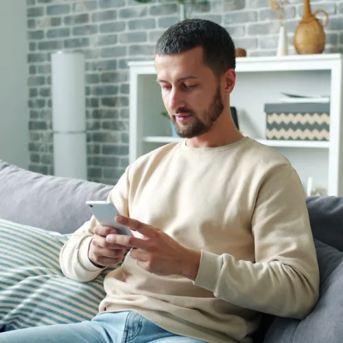 Dad calmly reading text message on couch. 