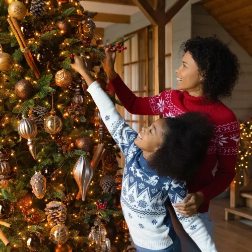 Mother and young daughter hanging ornaments on a Christmas tree