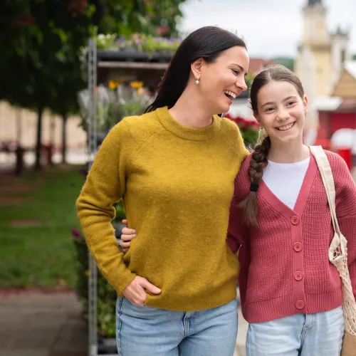 Mom and daughter walking side by side with their arms around each other