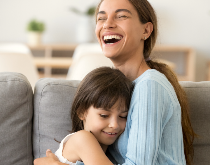 A mother holds her young daughter and smiles.