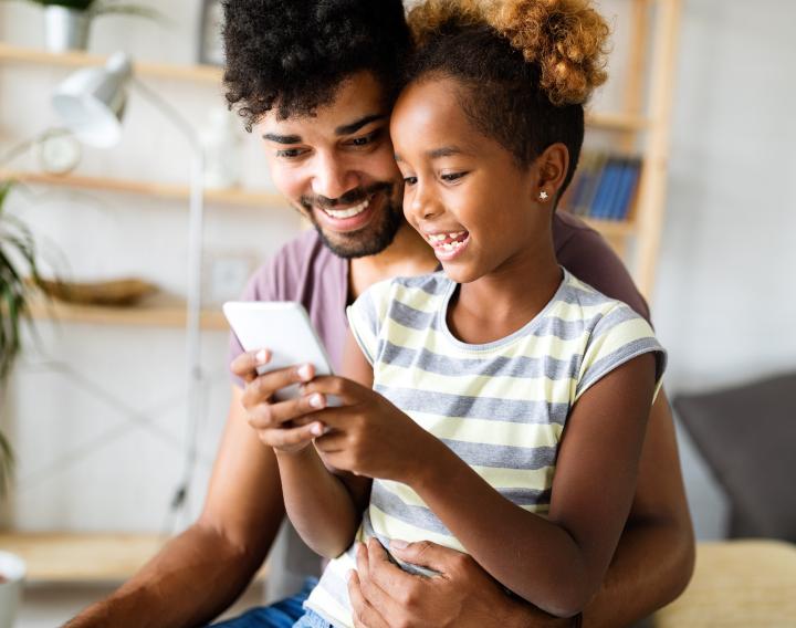 A father and daughter take a video call together on a smartphone