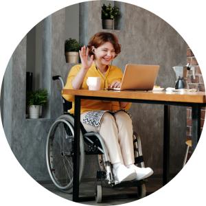 Woman sits at a table to attend a videoconference via her laptop.