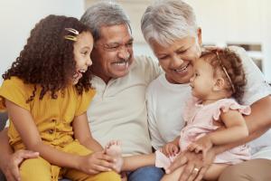 A grandfather and grandmother smile and hug two granddaughters
