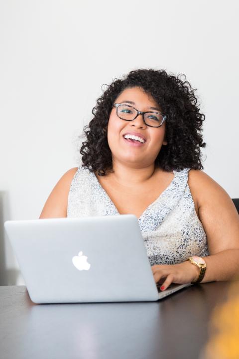 A woman smiles at her desk.