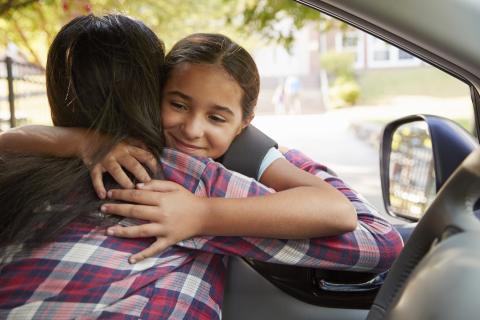 Daughter and mother hug to greet each other in the car.