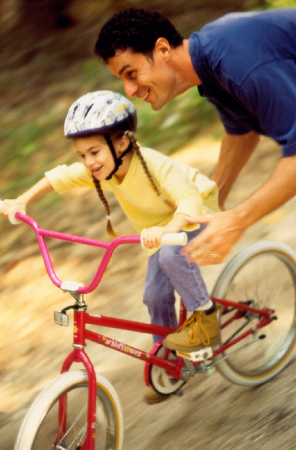 Father teaching daughter how to ride a bike