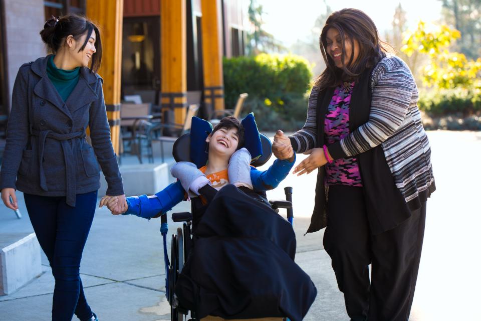 Two women and child in wheelchair enjoying the day outside