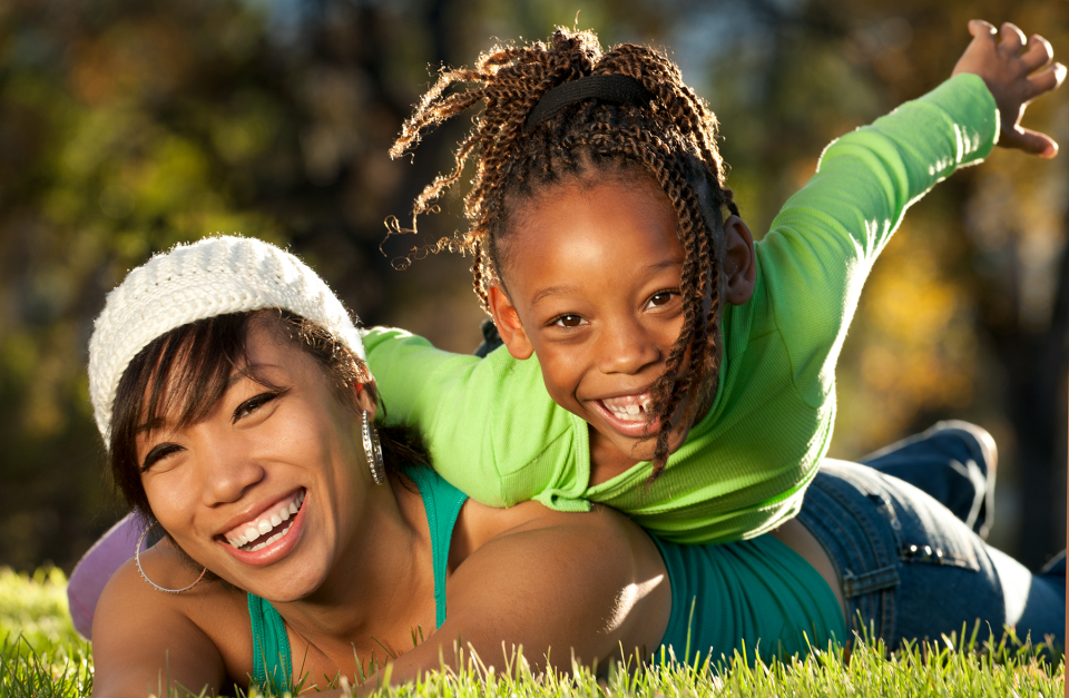 Mother and daughter playing outside in the grass on a sunny day