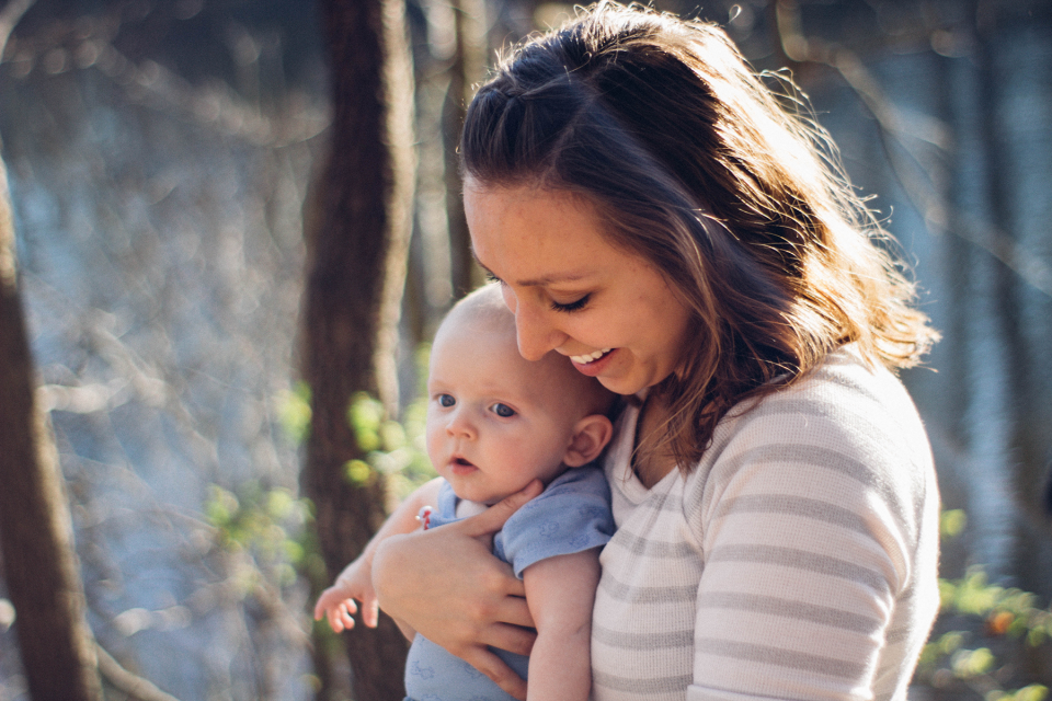 Smiling mother holds young infant outside