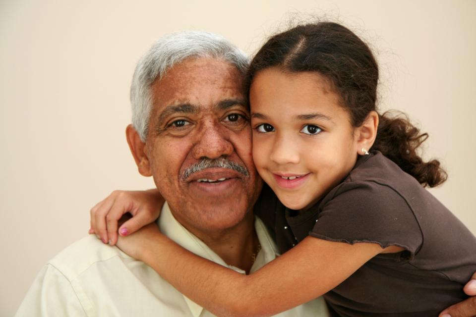 Granddaughter and grandfather hugging and smiling.