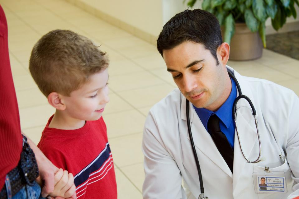 Doctor talks to young boy about his health.