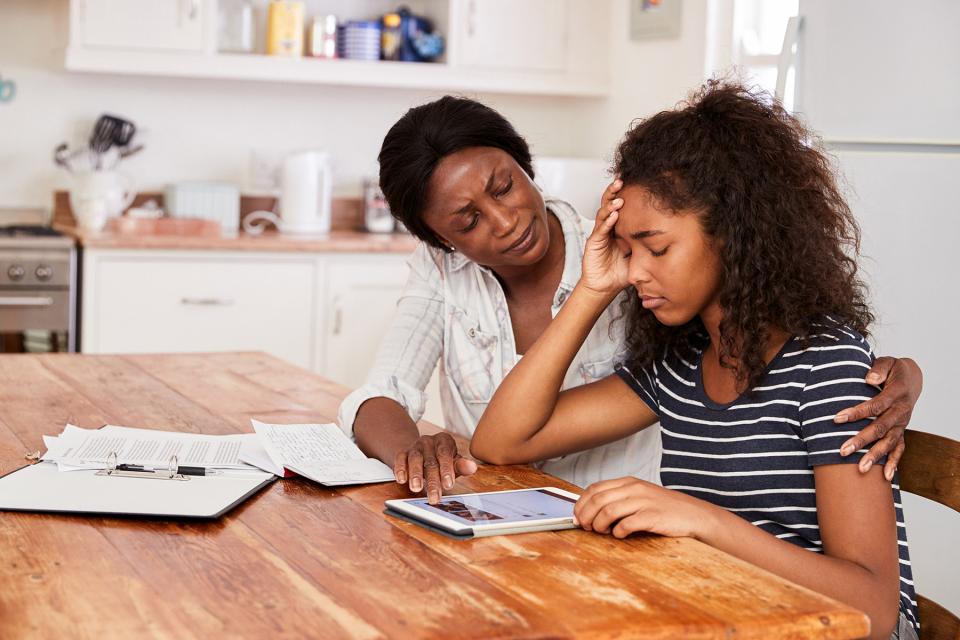 Mother puts arm around stressed daughter to comfort her.