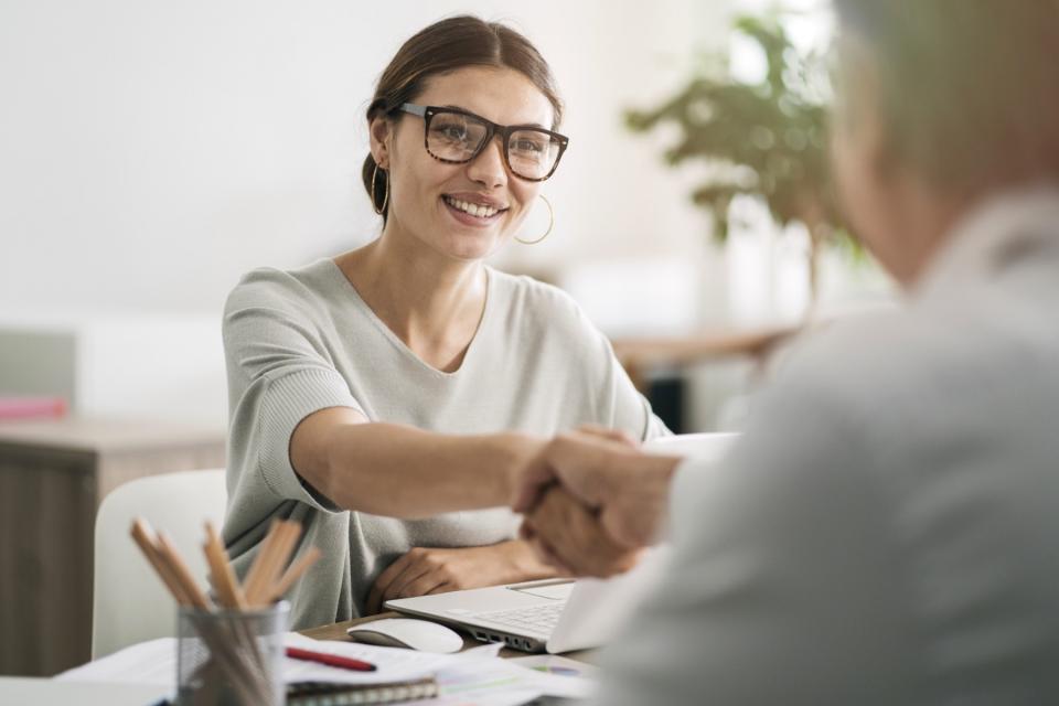 A professional woman shakes hands at a meeting.