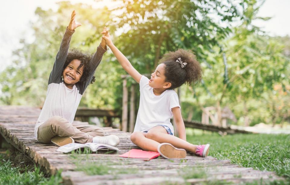 Two girls read outside on a sunny day.