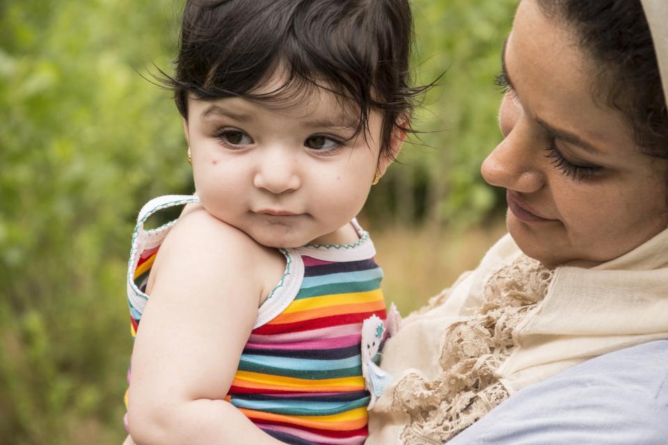 A mother holds her young child on a sunny day.