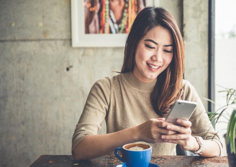 Woman looks at her phone over coffee. 