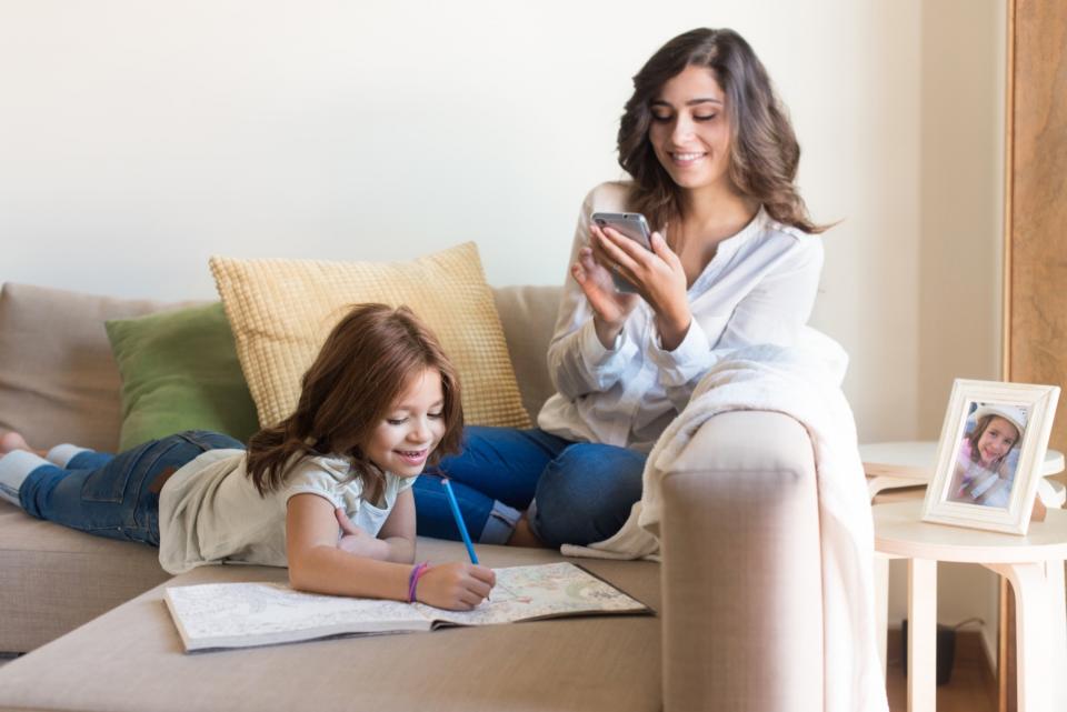 Mother and daughter relax together on the couch.