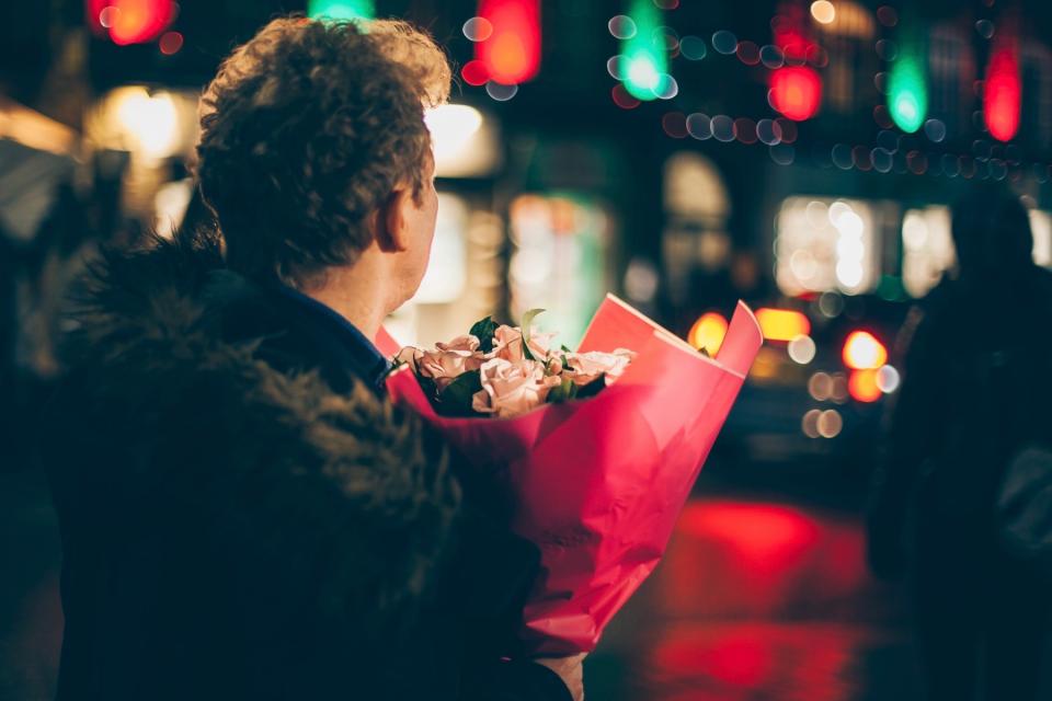 Man carries a bouquet of flowers on the street. 