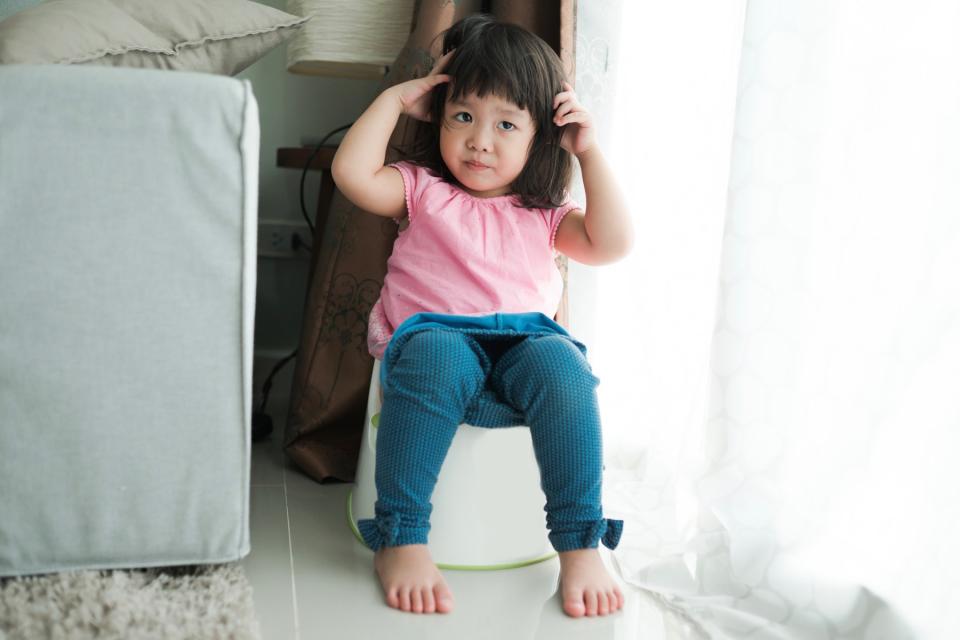 Young girl sits on a potty training toilet.