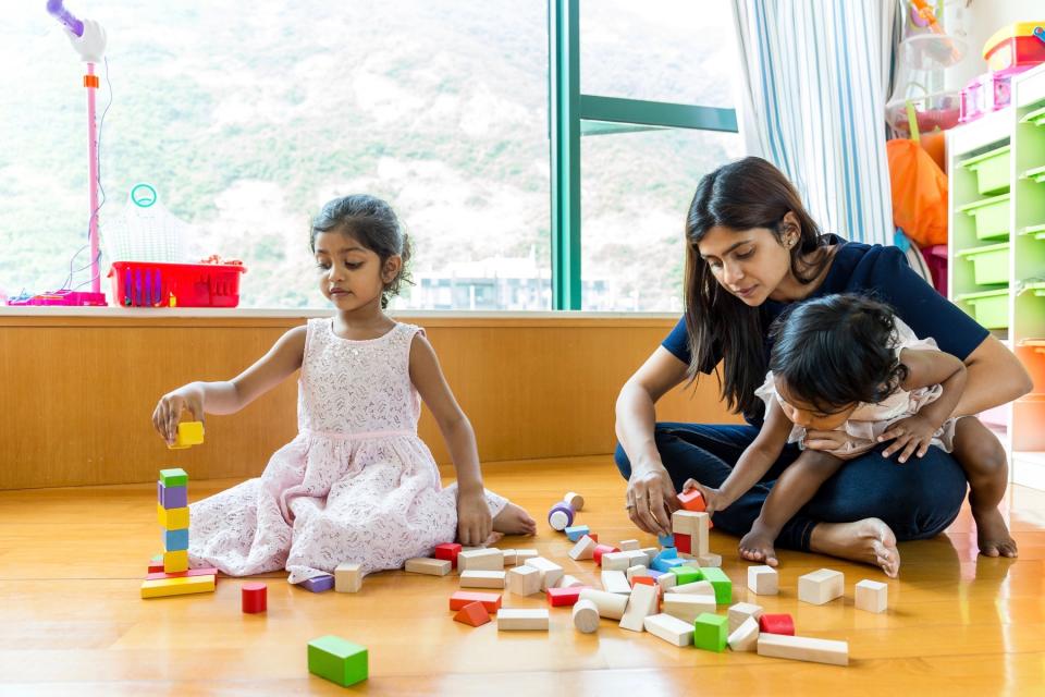 Mother and her children play with blocks together.