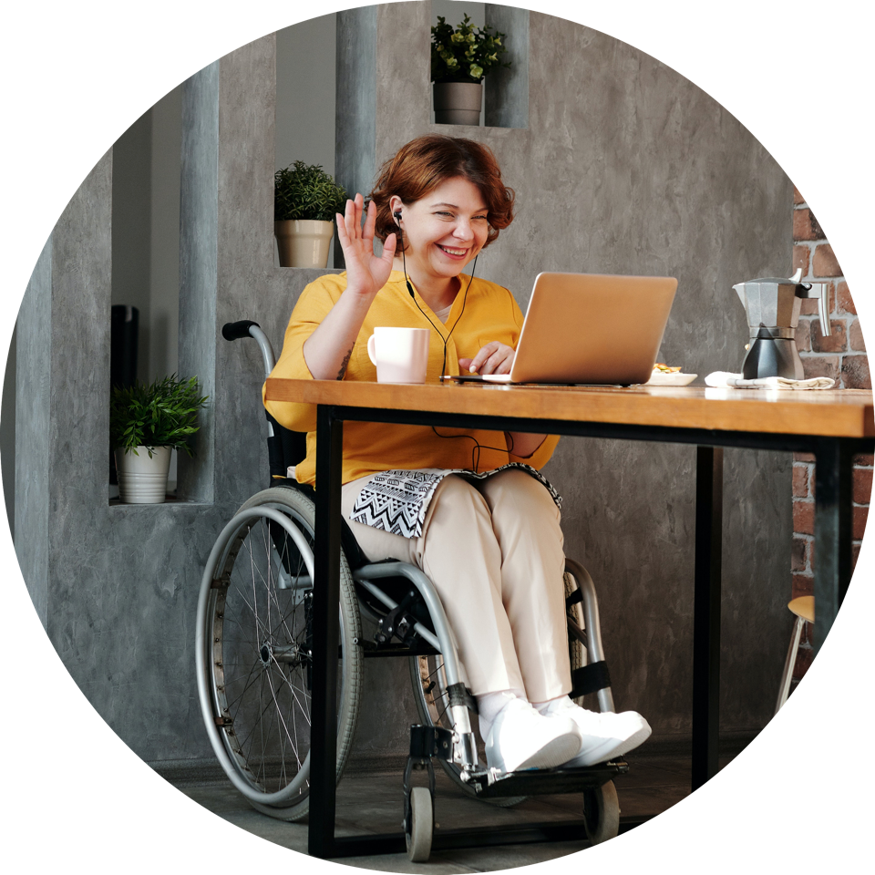 Woman sits at a table to attend a videoconference via her laptop.