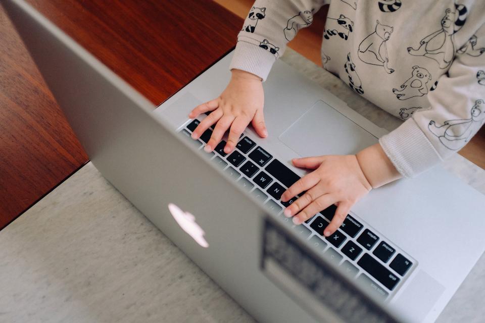 Baby stands in front of a laptop