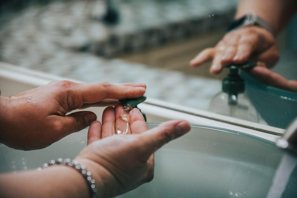 Person pumps soap into their palm as they wash their hands