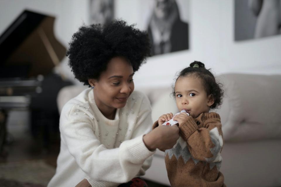 A mother helps to feed her young daughter.