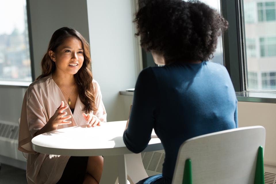 Two women sit at a coffee table