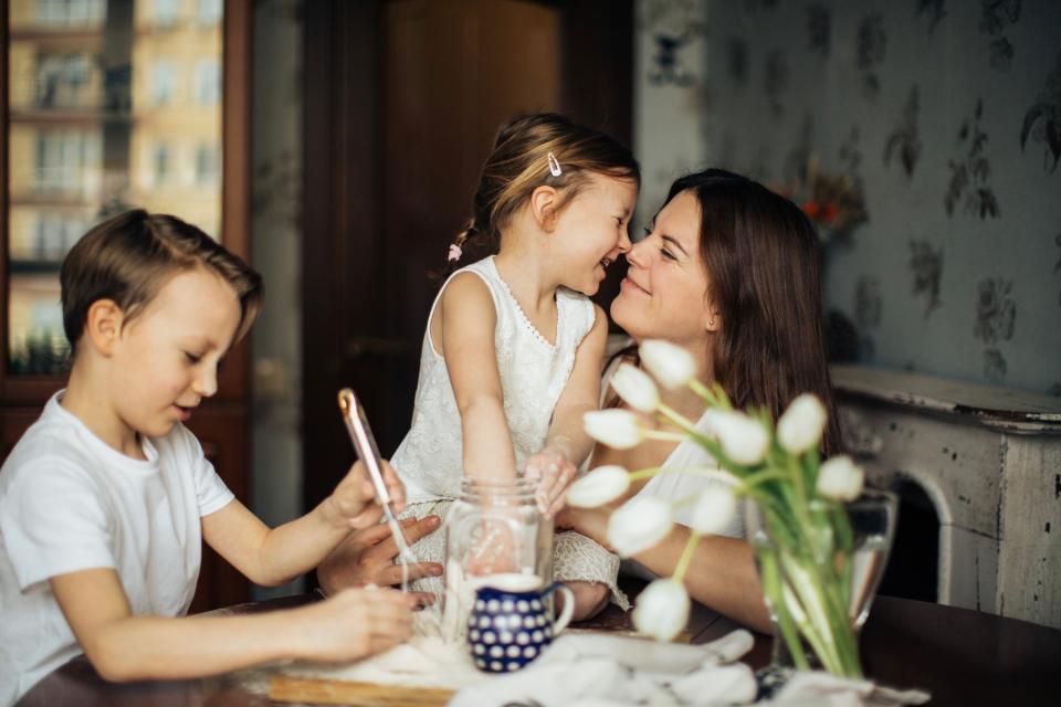 A mother shares a loving moment with her kids at the table.