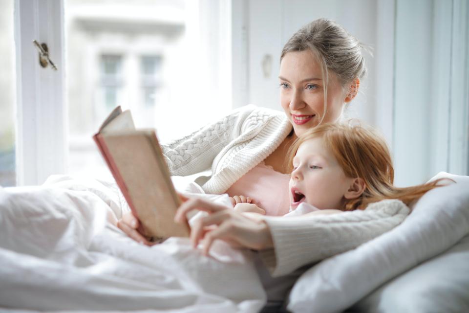 woman with child in bed reading
