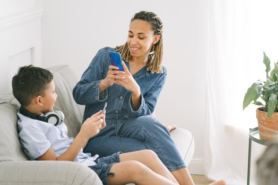 woman and child on couch with phone taking photo