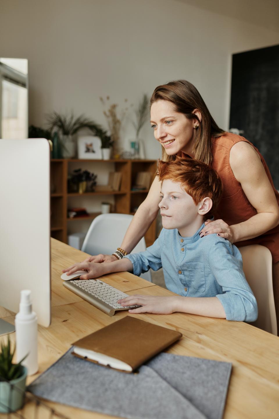 child being supervised on computer by an adult supervisor