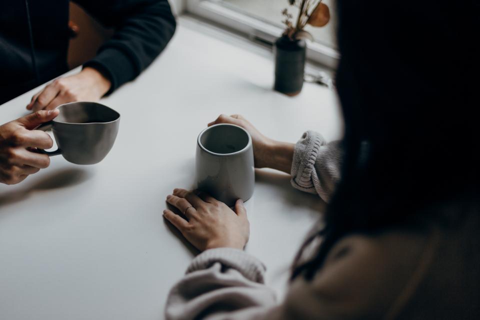 photo of two people having coffee with coffee cups on table