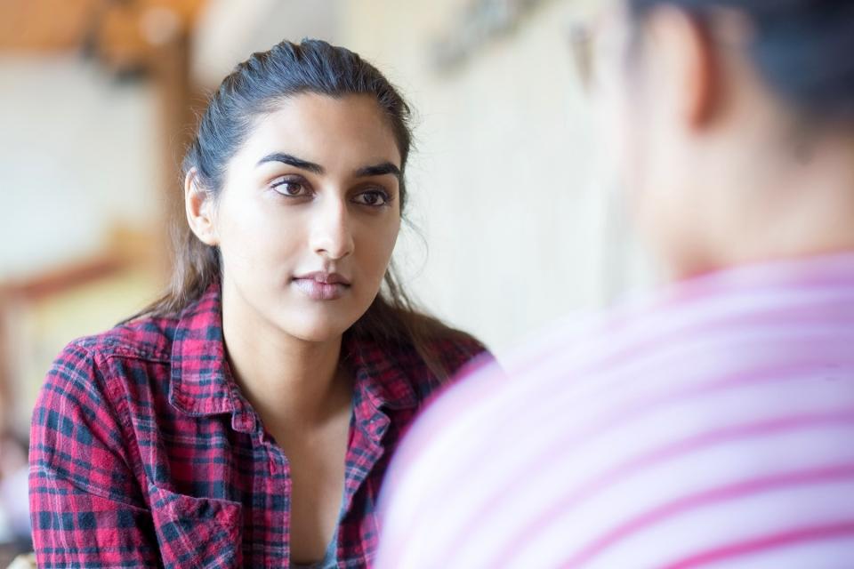 A woman listening, seen over the shoulder of a man who is facing her.