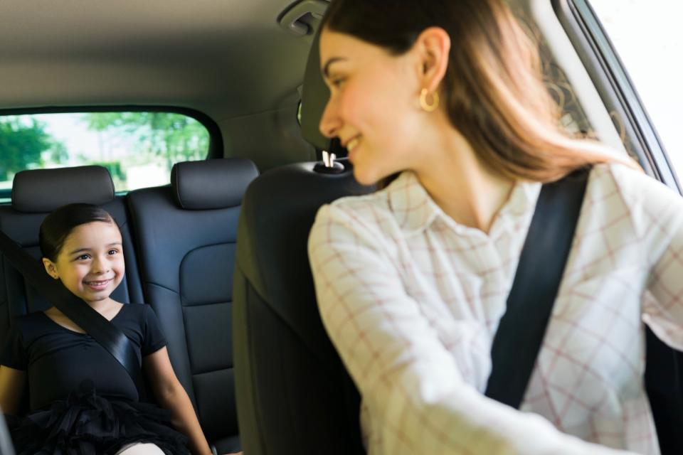 A mother looks back and smiles at her daughter while in the car.