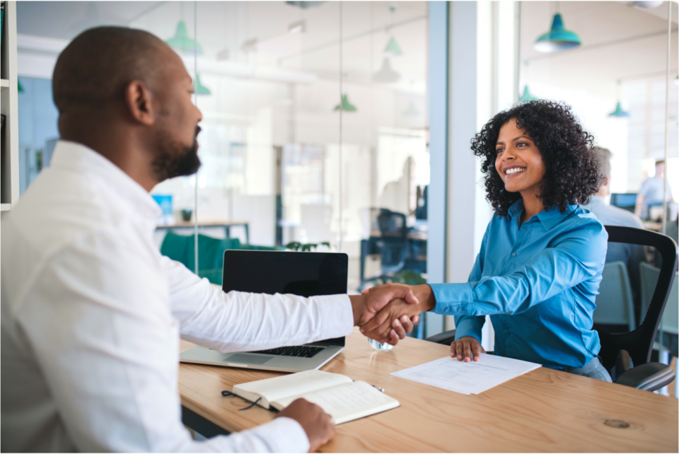 Family law attorney shakes hands from across a desk with a smiling client.