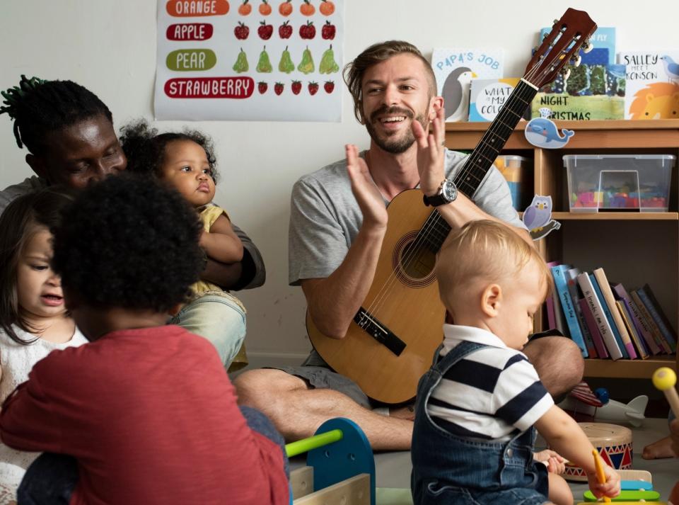 A man playing guitar for a group of children