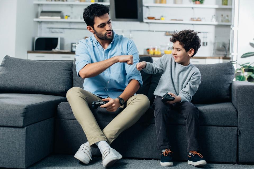 Father and son fist bumping on couch.