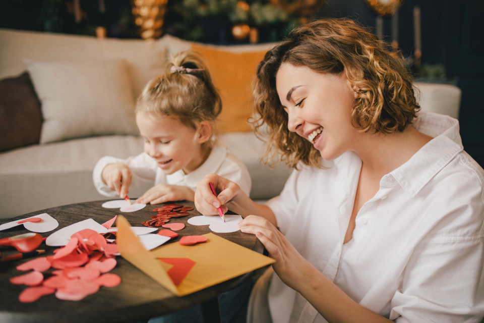 Mom and daughter making paper hearts.