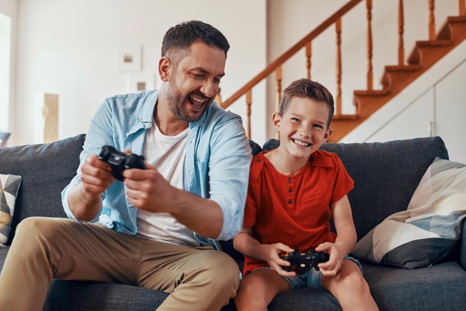 Man and son playing video games on couch. 