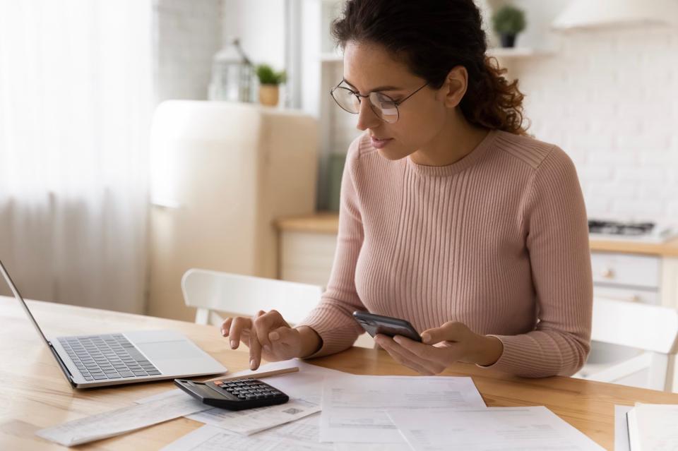 Woman uses a calculator while calculating bills and taxes