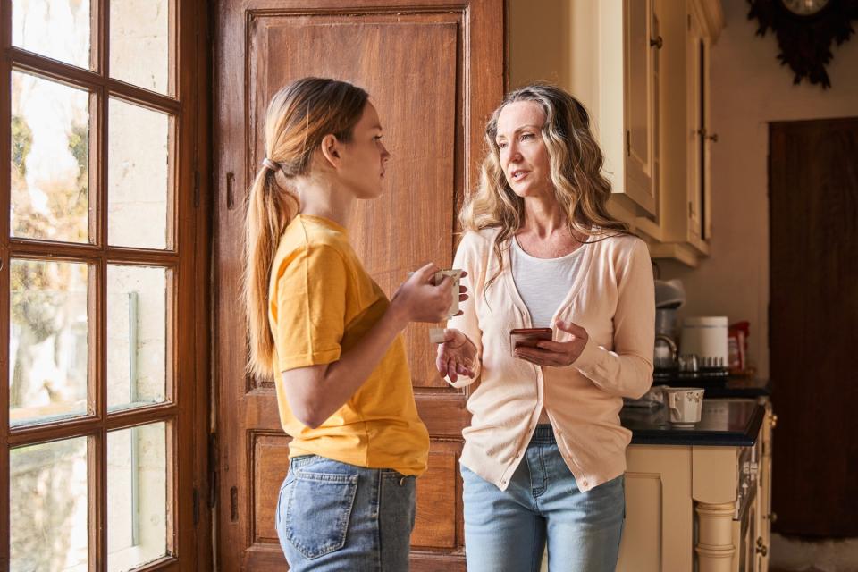 Mother and daughter talk in the kitchen while drinking coffee