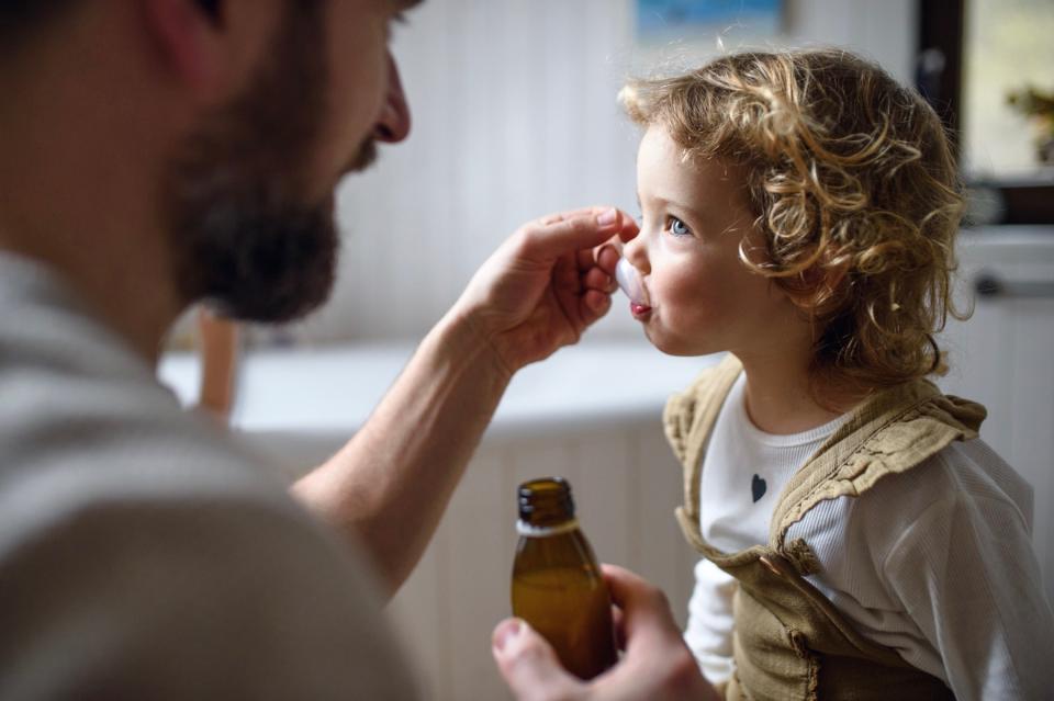 Dad giving daughter medicine. 